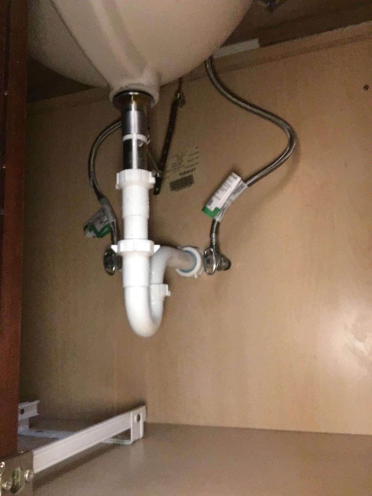 New sink drain and water supply connections beneath a cabinet